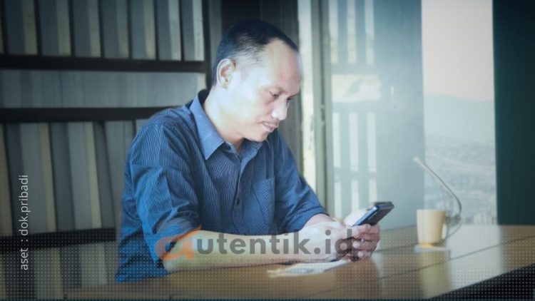 Ketua Desk Pilkada Gerindra Pohuwato, Arfan Dalanggo sedang duduk menggunakan handphone.